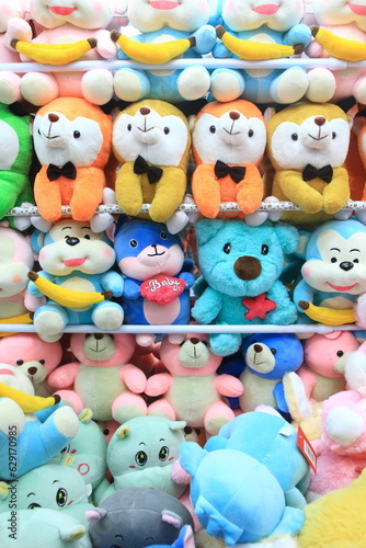 Row of colorful stuffed animal dolls inside claw crane game.