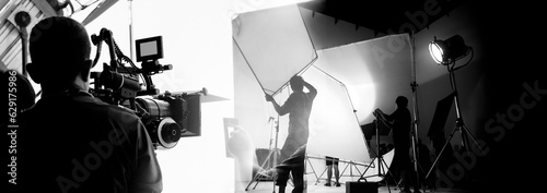 Silhouette of video production behind the scenes or B roll or making of TV commercial movie that film crew team lightman and cameraman working together with director in big studio with pro equipments photo