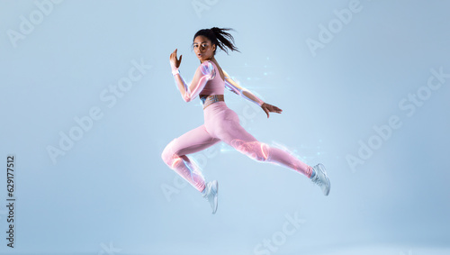 Futuristic training concept. Fit black woman in sportswear jumping, running