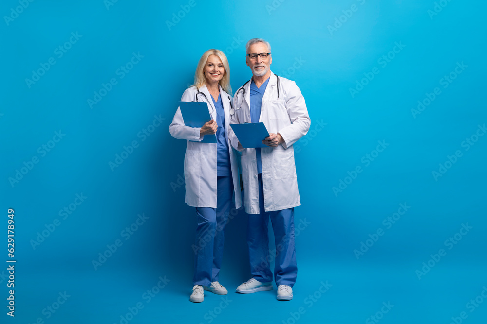 Senior doctors professional medical team posing on blue background Senior doctors professional medical team posing on blue background