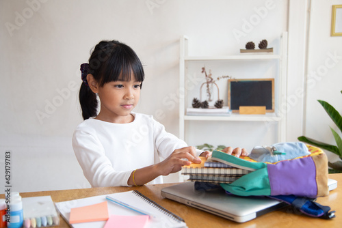 Pupil child put books and notes into backpack. School supplies.Back to school concept. Kid prepare for studies. Portrait cute little girl packing backpack .