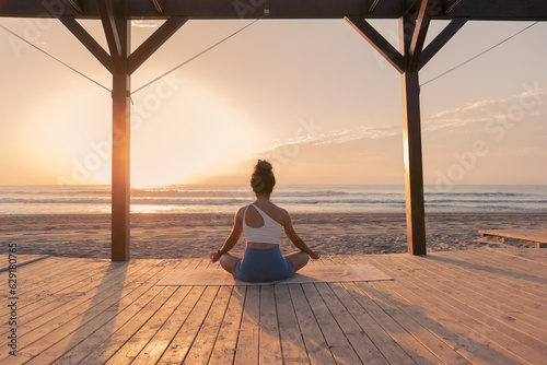 Woman on the beach at sunrise in meditation pose