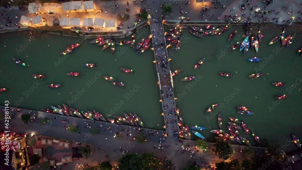 Vue aérienne de la l'ancienne ville de Hoian au Vietnam de nuit. On y voit les bateaux illuminés par des lanterne sur la rivière. Cette ville est inscrite au patrimoine mondiale de l'Unesco.