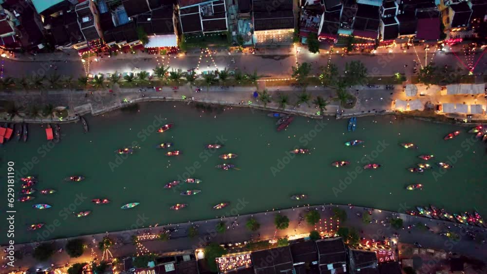Vue aérienne de la l'ancienne ville de Hoian au Vietnam de nuit. On y voit les bateaux illuminés par des lanterne sur la rivière. Cette ville est inscrite au patrimoine mondiale de l'Unesco.