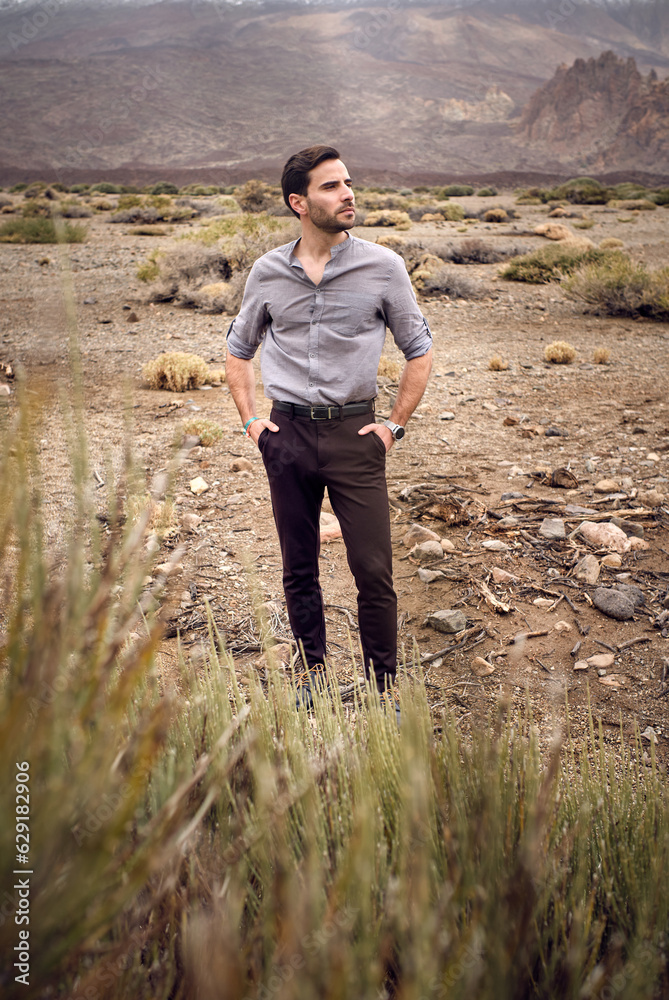 Φωτογραφία Stylish young male standing in rocky valley with savanna grass
