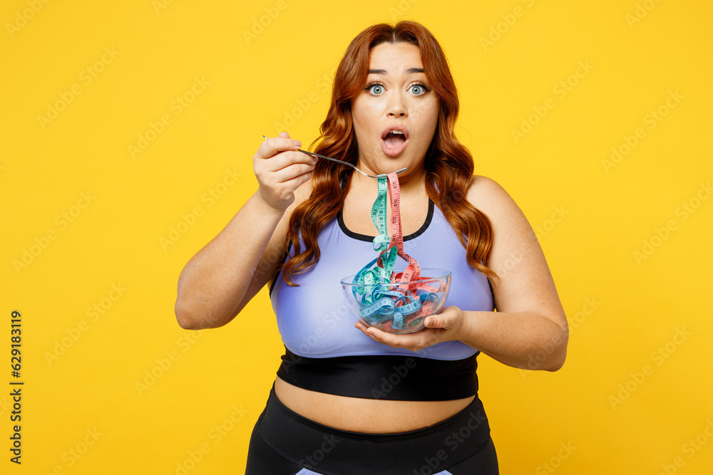 Young sad chubby overweight plus size big fat fit woman wear blue top warm up training hold bowl with measure tape pov eating isolated on plain yellow background studio home gym Workout sport concept Young sad chubby overweight plus size big fat fit woman wear blue top warm up training hold bowl with measure tape pov eating isolated on plain yellow background studio home gym Workout sport concept