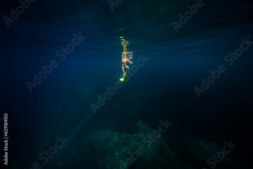 Anonymous man diving in deep blue ocean