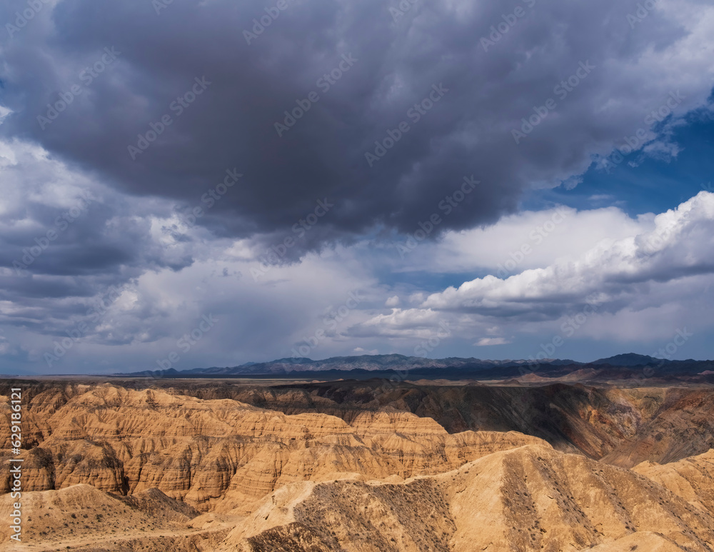 Lunar yellow canyon with clay mountains under a dramatic sky with clouds in Charyn National Park in Kazakhstan near city of Almaty