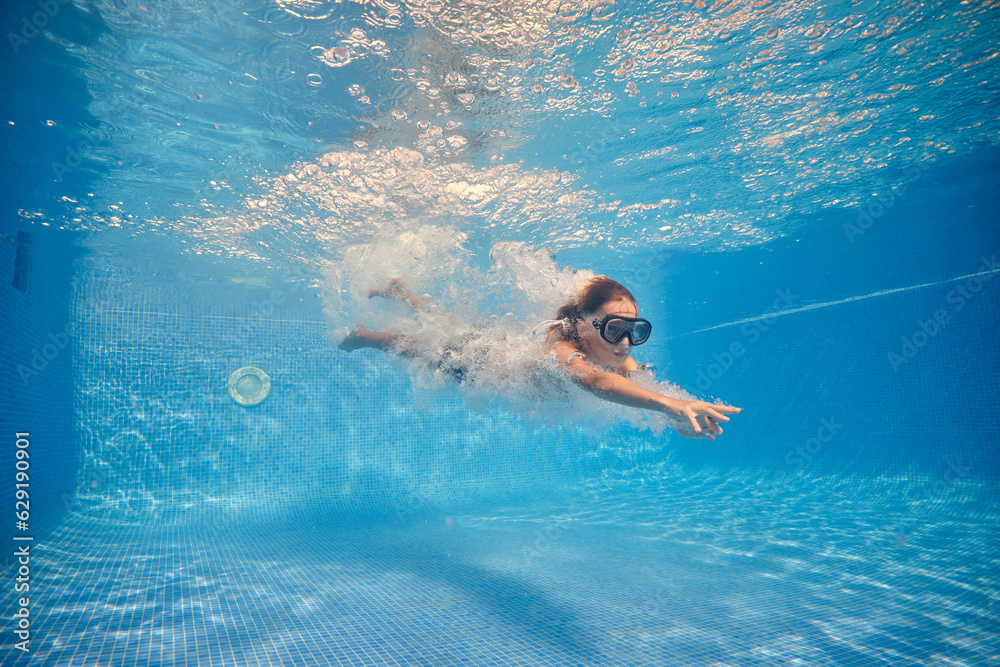 Active boy swimming underwater of clear pool
