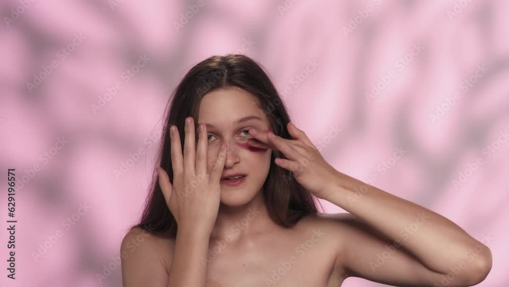 Beautiful brunette model with natural makeup and pink eye patch looking at the camera Beautiful brunette model with natural makeup and pink eye patch looking at the camera