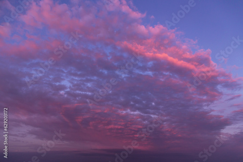 Sunset pink purple violet cloudy sky. Beautiful sunrise with pink clouds against blue sky background texture © Viktor Iden