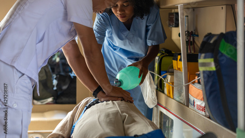 Two rescuers helping a patient to breath properly in am ambulance van. Paramedics work together to let patient get enough oxygen.