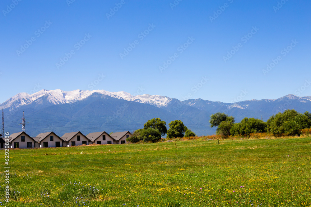 Panoramic view of houses against the backdrop of mountains and a meadow with wildflowers in Bulgaria