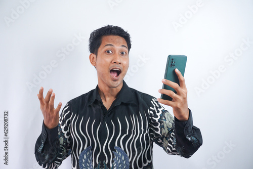 Photo of positive excited man screaming and looking cellphone isolated over white background © AriaSandi