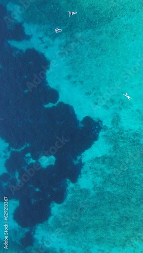 Aerial view of boats in crystal clear blue ocean waters of Corfu Island in Greece.
