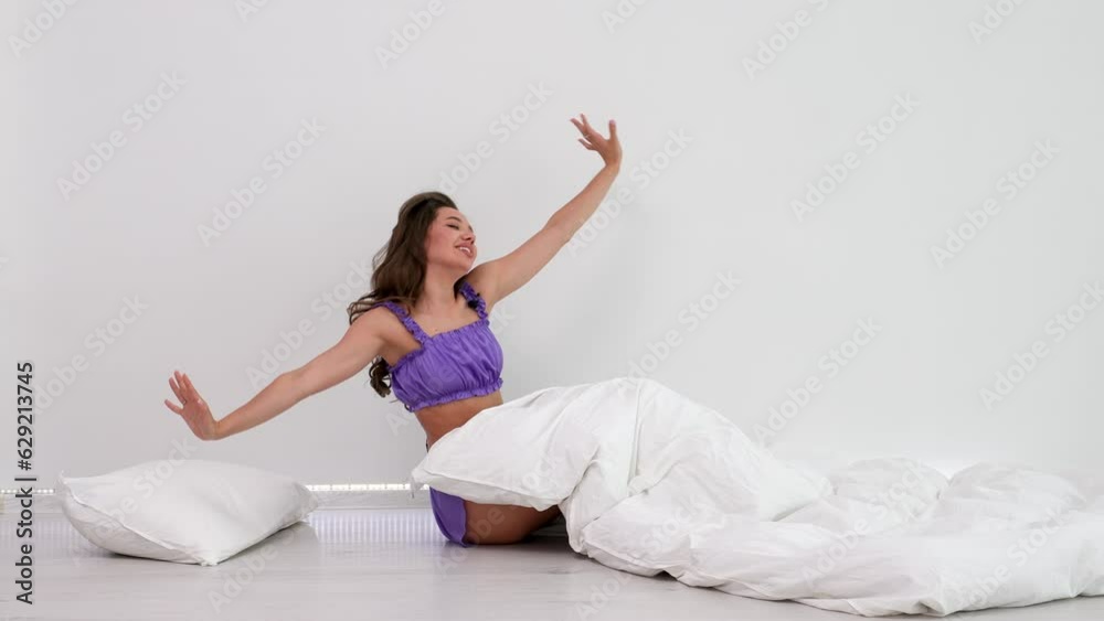Tired sleepy woman waking up and yawning with a stretch while sitting in bed isolated on white background Tired sleepy woman waking up and yawning with a stretch while sitting in bed isolated on white background