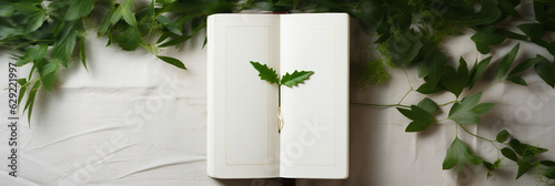an open notebook, a book with blank pages on a white wooden background with weeping greenery, ivy . Bright sunny photography for mockups, presentations and publications.