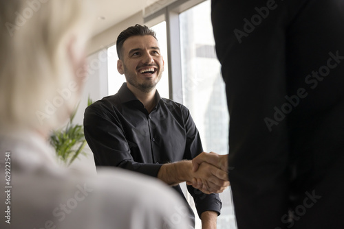 Happy candidate man getting job, shaking hands with employer after successful interview. Entrepreneur giving handshake to business partner, gesture of cooperation, friendship, partnership