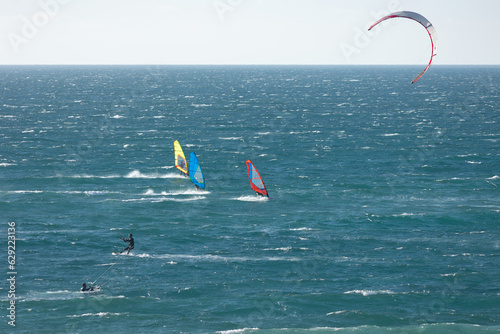 People are engaged in different types of surfing in the blue ocean