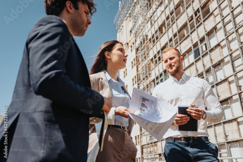 Young architect team discussing project profitability out in the city, on a beautiful sunny day photo