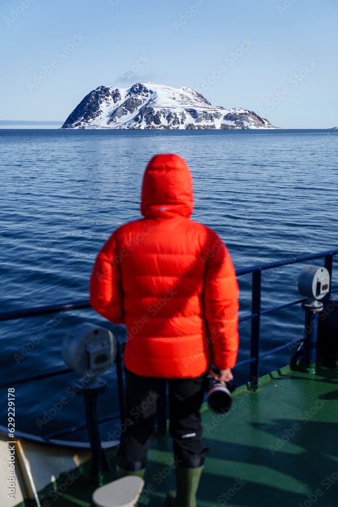 Man looking at arctic mountain from a ship Man looking at arctic mountain from a ship