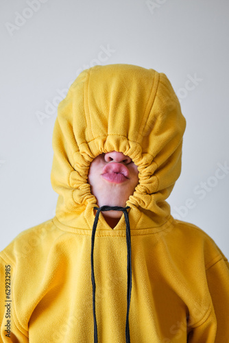 Unrecognizable child making grimace in yellow hoodie