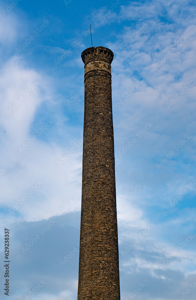Old brick chimney on blue cloudy sky
