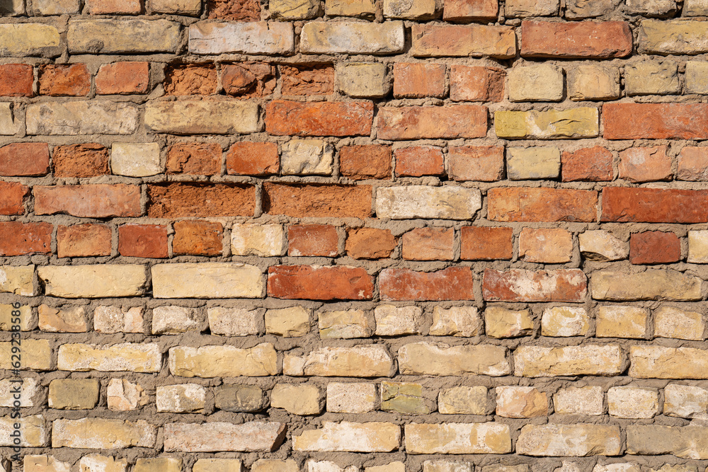 Obraz premium A texture of concrete wall of old red and yellow clay bricks.