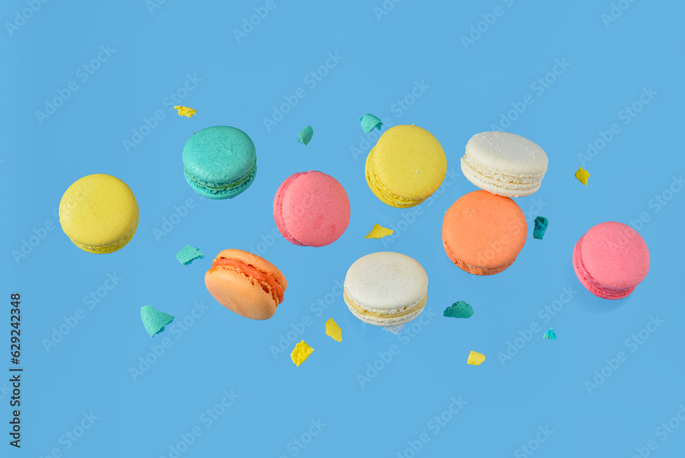 Fototapeta premium Flying sweet macaroons on blue background