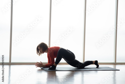 Young caucasian woman practicing yoga with strength in fitness gym, sport and flexibility, woman training workout and exercise with motivation for health, stretch muscular for wellness and meditation.