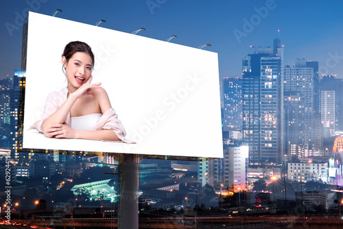 Portrait of beautiful charming young Asian woman posing facial and sitting with white table advertise on billboard blank for outdoor advertising poster or blank billboard for advertisement