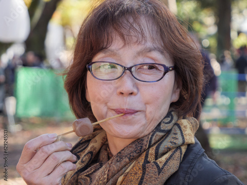 An older Japanese woman eating dango