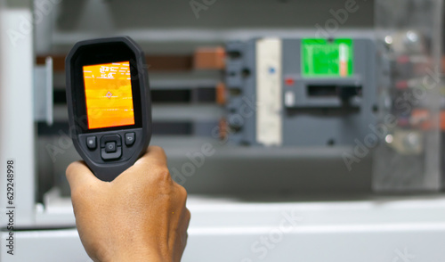 Professional Electrician use thermal infrared camera or thermometer scaning electrical system for preventive maintenance,Industrial thermography,Thermal image of power electric. photo