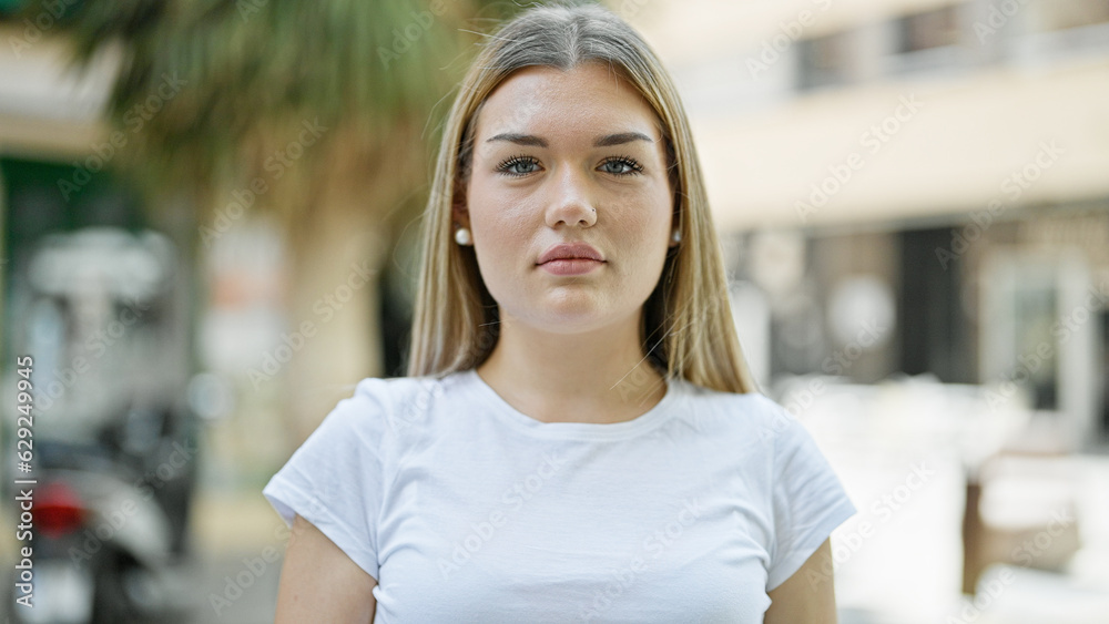 Young blonde woman standing with serious expression at street