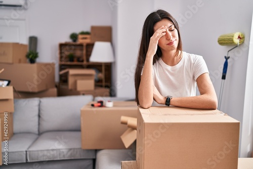 Young beautiful hispanic woman leaning on package with worried expression at new home © Krakenimages.com