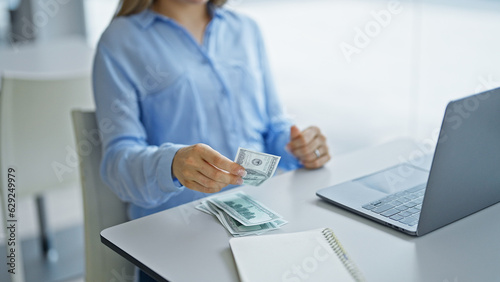 Young blonde woman business worker using laptop counting dollars at office