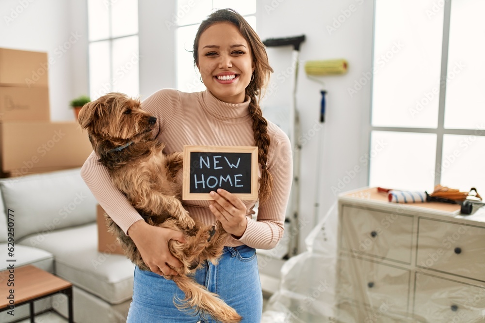 Young beautiful hispanic woman hugging dog holding blackboard at new home Young beautiful hispanic woman hugging dog holding blackboard at new home
