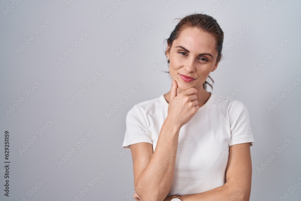 Beautiful brunette woman standing over isolated background looking confident at the camera smiling with crossed arms and hand raised on chin. thinking positive. Beautiful brunette woman standing over isolated background looking confident at the camera smiling with crossed arms and hand raised on chin. thinking positive.