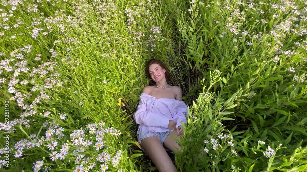 beautiful woman lies in the grass chamomile flowers happy summer. The concept of rest and new life of a woman. beautiful woman lies in the grass chamomile flowers happy summer. The concept of rest and new life of a woman.