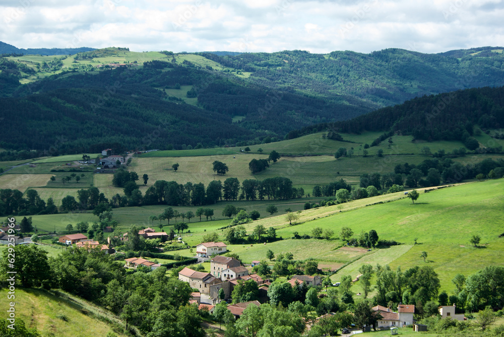 Small village in an agricultural landscape with volcano mountains in Auvergne in France.