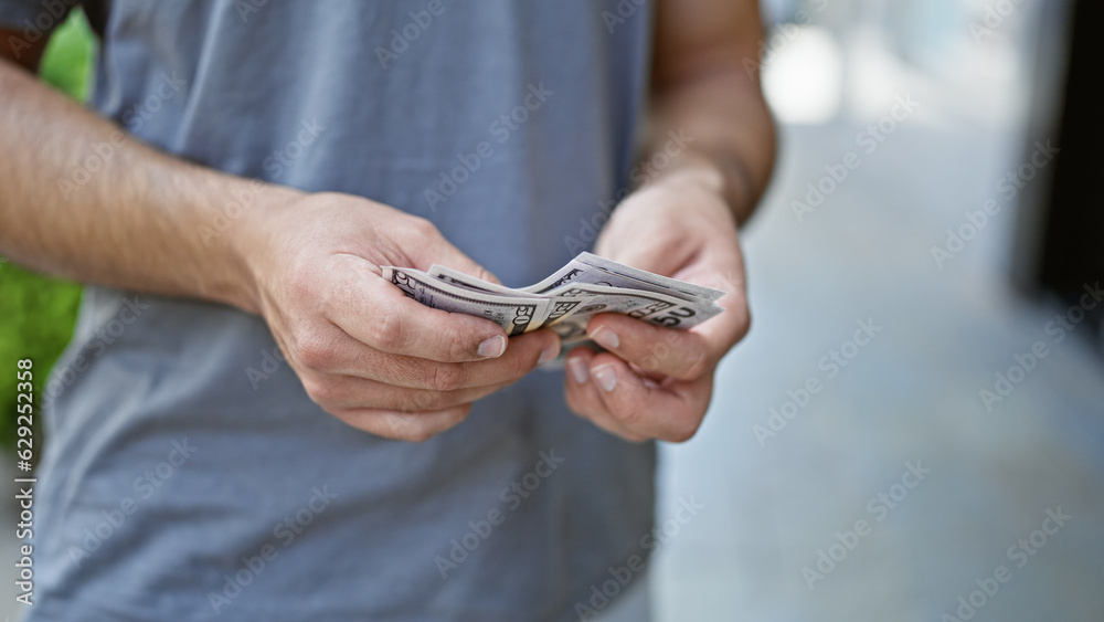 Young latin man smiling confident counting dollars at street