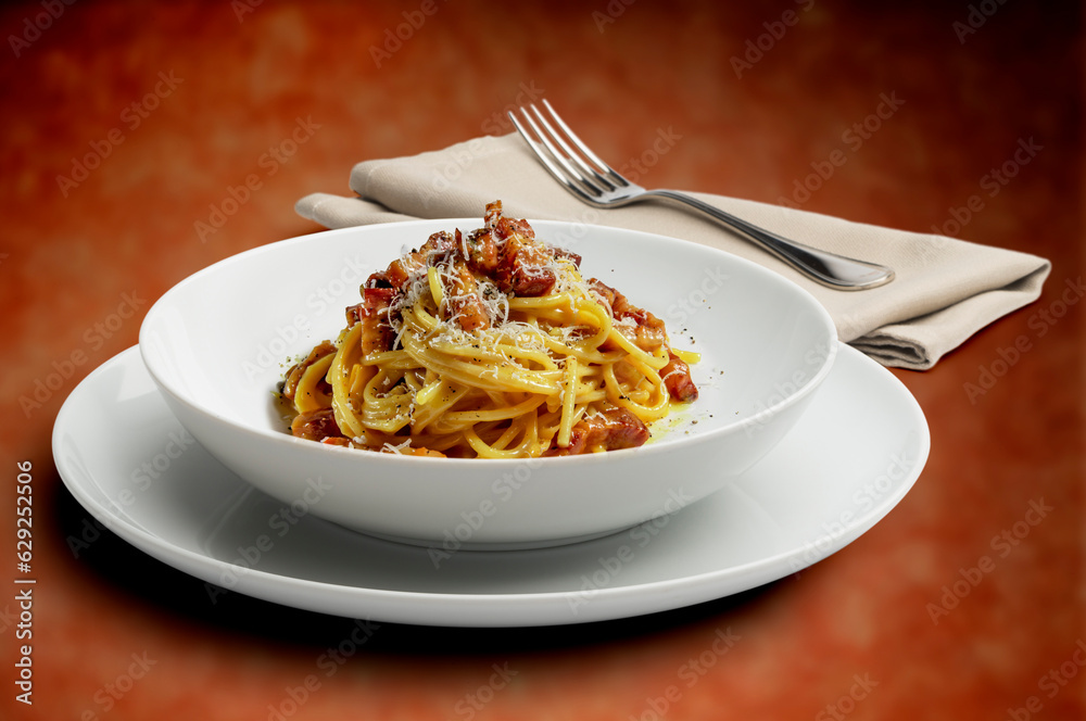 Plate with spaghetti alla carbonara on a speckled background