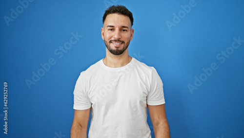 Young arab man smiling confident standing over isolated blue background © Krakenimages.com