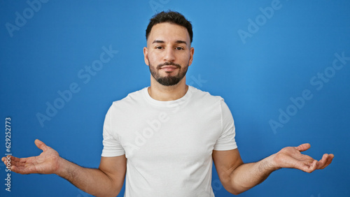 Obraz na płótnie Young arab man standing clueless over isolated blue background