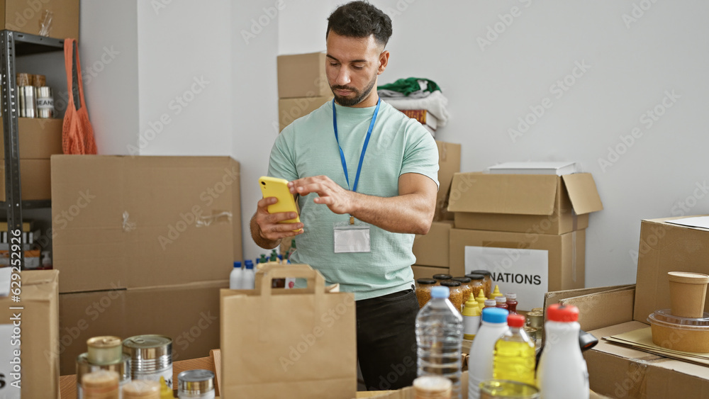 Φωτογραφία Young arab man volunteer make photo to products by smartphone at charity center