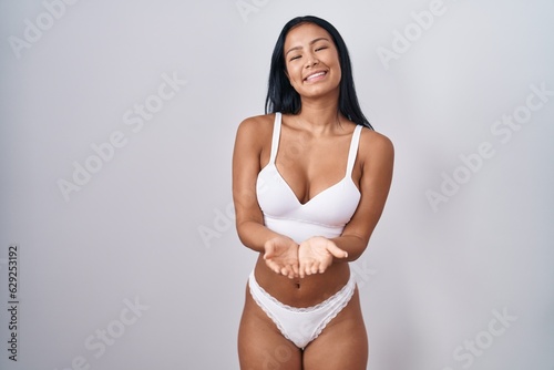 Hispanic woman wearing lingerie smiling with hands palms together receiving or giving gesture. hold and protection © Krakenimages.com