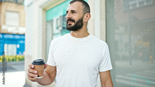 Young hispanic man drinking coffee at street