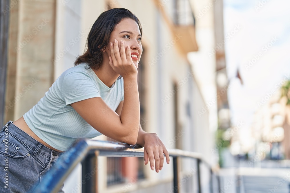 Young hispanic woman smiling confident looking to the side at street