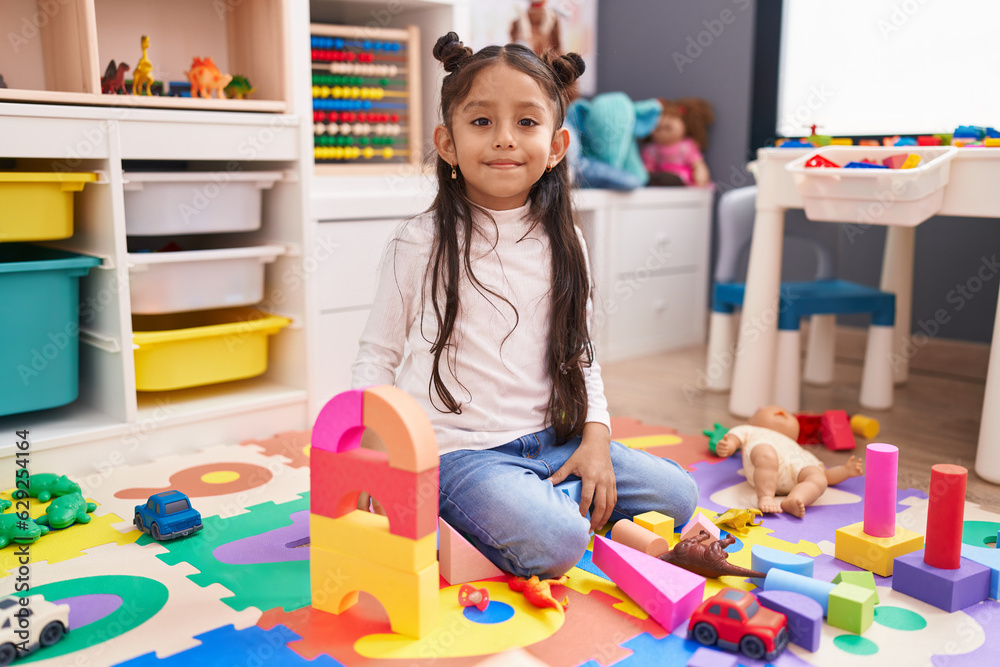 © Krakenimages.com - Adorable hispanic girl playing with construction blocks sitting on floor at kindergarten © Krakenimages.com - Adorable hispanic girl playing with construction blocks sitting on floor at kindergarten