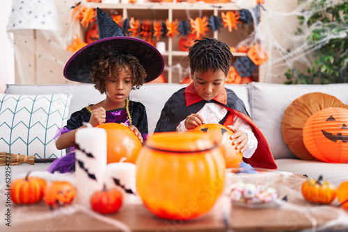 Adorable african american boy and girl having halloween party drawing on balloon at home